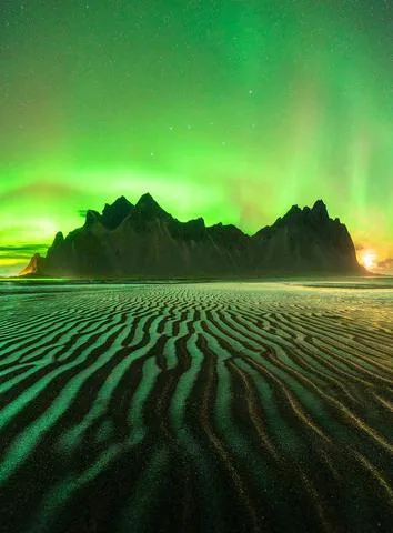 Fig. 4 Aurora boreal vista sobre una montaña rocosa de Vestrahorn, Stokksnes, Islandia. Luces polares causadas por partículas del viento solar que excitan átomos de la termosfera. Crédito: Astrofotógrafo Lorenzo Ranieri Tenti de National Geographic.
